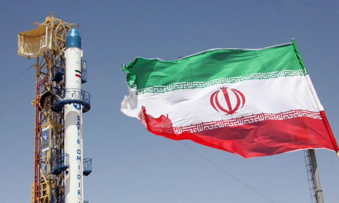 Una imagen tomada el 16 de agosto de 2008 muestra una bandera iraní ondeando frente al cohete Safir Omid de Irán. (Vahidreza Alai/AFP a través de Getty Images)