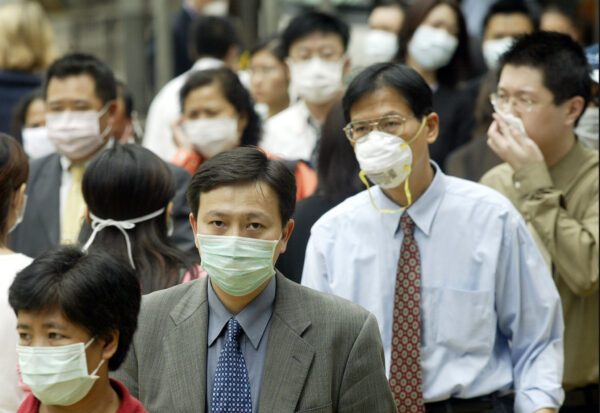 La gente usa mascarillas en la calle para protegerse contra un virus mortal de neumonía en Hong Kong, el 31 de marzo de 2003. (Peter Parks/AFP/GettyImages)