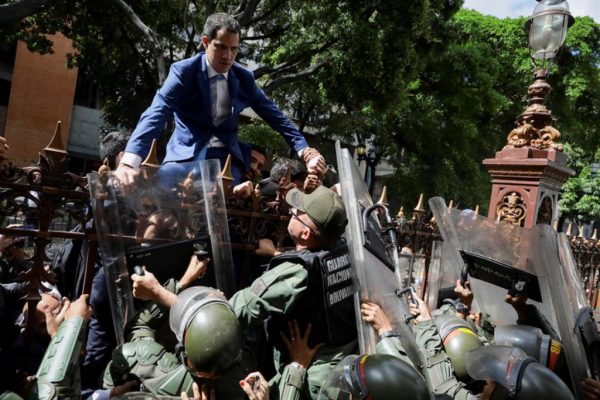 Juan Guaidó escala uma cerca na tentativa de entrar na sede da Assembleia Nacional, vigiada pela polícia a fim de impedir sua entrada e a de deputados da oposição neste domingo, em Caracas, Venezuela (EFE / Rayner Peña)