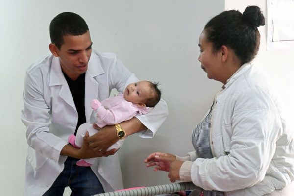 Médico cubano Miguel Pantoja segura um bebê nos braços na Unidade Básica de Saúde de Alexania, localizada a 80 km a sudoeste de Brasília, estado de Goiás, em 22 de novembro de 2018 (EVARISTO SA / AFP / Getty Imagens)