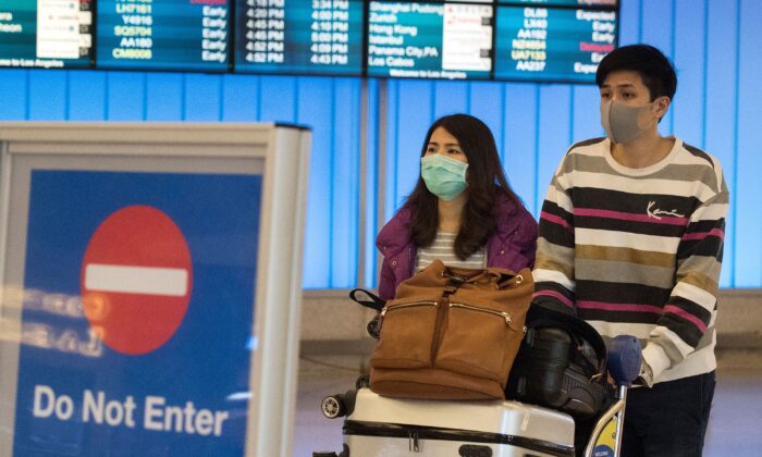 Pasajeros usan máscaras protectoras para protegerse contra la propagación del coronavirus cuando llegan al Aeropuerto Internacional de Los Ángeles, California, el 22 de enero de 2020. (Mark Ralston/AFP a través de Getty Images)