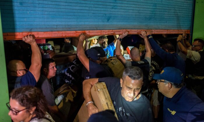 La policía se aproxima mientras la gente irrumpe en un almacén lleno de suministros en Ponce, Puerto Rico, el 18 de enero de 2020. (Ricardo Arduengo/AFP/Getty Images)
