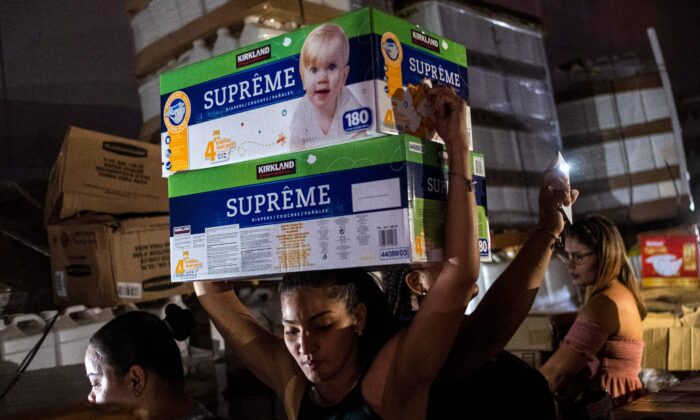Una mujer lleva cajas de pañales para bebés desde un almacén lleno de suministros, incluidos miles de cajas de agua, que se cree fueron recibidos como ayuda a los damnificados  cuando el huracán María azotó la isla en 2017 en Ponce, Puerto Rico, el 18 de enero de 2020. (Ricardo Arduengo / AFP a través de Getty Images)