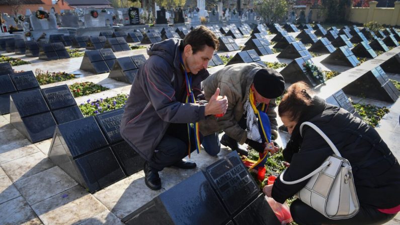 La gente enciende velas en el Cementerio de los Héroes de la Revolución de 1989 para conmemorar el 30 aniversario de las primeras víctimas de la revolución rumana en Timisoara, el 15 de diciembre de 2019. (DANIEL MIHAILESCU / AFP a través de Getty Images)
