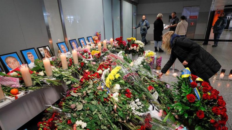 Uma mulher traz flores enquanto presta homenagem a retratos de tripulantes do voo PS752 da Ukraine International Airlines no aeroporto internacional de Boryspil, em Kiev, na Ucrânia, em 11 de janeiro de 2020. De acordo com relatos da mídia em 11 de janeiro de 2020, os militares iranianos divulgaram um comunicado alegando que O voo PS752 da Ukraine International Airlines foi abatido devido a 'erro humano' (EFE / EPA / SERGEY DOLZHENKO)
