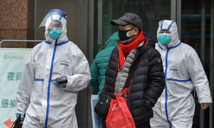 Personal médico con ropa para protegerse contra un virus previamente desconocido camina fuera de un hospital en Wuhan el 26 de enero de 2020, una ciudad en el epicentro de un brote viral que ha matado al menos a 56 personas e infectado a casi 2000. (Hector RETAMAL/AFP vía Getty Images)