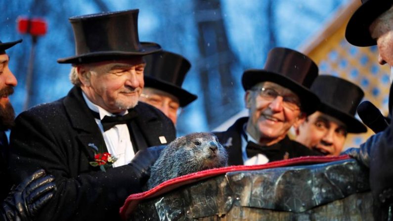 Los miembros del círculo del club de la marmota observan cómo Phil de Punxsutawney hace su predicción durante la celebración del Día de la Marmota en Gobblers Knob, Punxsutawney (Pennsylvania), EE.UU., el 2 de febrero de 2020. (EFE/EPA/David Maxwell)