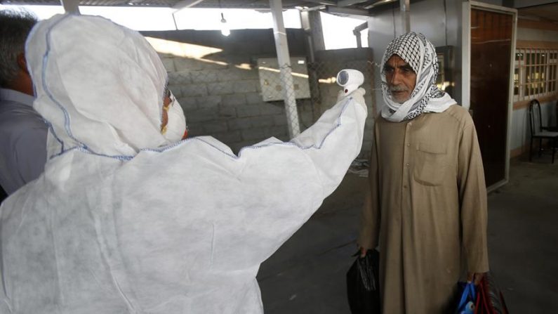 Un miembro del equipo médico comprueba la temperatura corporal de un hombre iraquí a su llegada al paso fronterizo de Shalamcheh con Irán, al este de la ciudad de Basora, a 500 km al sur de Iraq, el 20 de febrero de 2020. (Basora) EFE/EPA/HAIDER AL-ASSADEE
