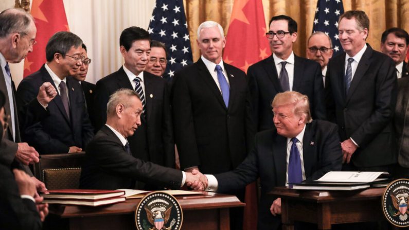 El viceprimer ministro chino Liu He (L) y el presidente de los Estados Unidos, Donald Trump, durante la firma de la primera fase de un acuerdo comercial, rodeado de funcionarios, en la Sala Este de la Casa Blanca en Washington el 15 de enero de 2020. (Charlotte Cuthbertson/The Epoch Times)