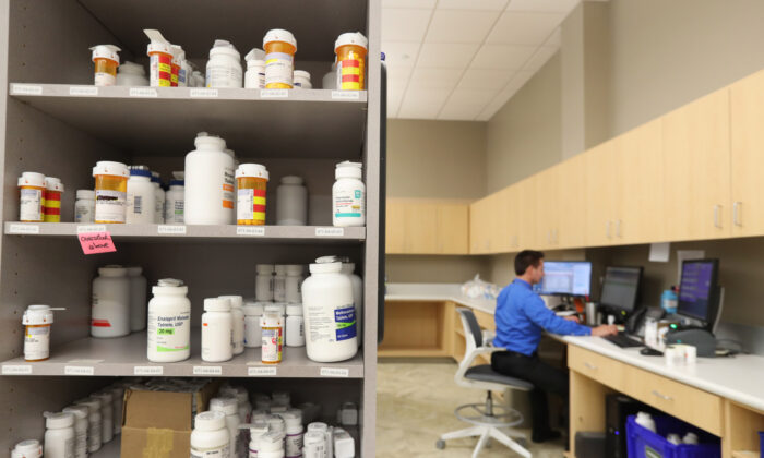 Un técnico farmacéutico trabaja en una computadora mientras los frascos de medicamentos están en los estantes de la farmacia central de Intermountain Heathcare en Midvale, Utah, el 10 de septiembre de 2018. (George Frey/Getty Images)