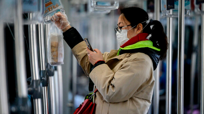 Una mujer que llevaba una máscara protectora usa su teléfono móvil mientras viajaba en un tren en Shanghai el 20 de febrero de 2020. (Noel Celis/AFP a través de Getty Images)