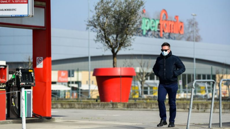 Un hombre con una máscara quirúrgica pasa por una gasolinera en Codogno, al sureste de Milán, el 22 de febrero de 2020. - Las calles estaban desiertas y se advirtió a los residentes que se mantuvieran alejados de una sala de emergencias el 22 de febrero de 2020 en la ciudad italiana de Codogno, que se encontraba bajo cierre, ya que una segunda muerte por coronavirus despertó temores en toda la región. (MIGUEL MEDINA/AFP/Getty Images)