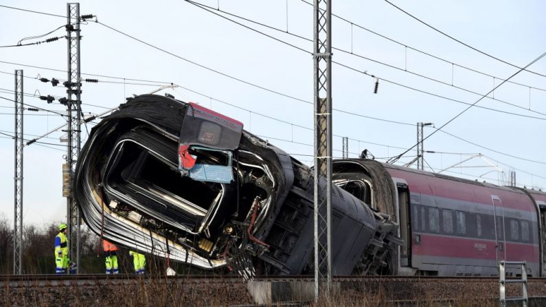 Miembros del equipo de rescate se reúnen frente a un vagón dañado en el sitio de un tren descarrilado, en las afueras de la ciudad de Lodi, cerca de Milán, norte de Italia, el 6 de febrero de 2020. (MIGUEL MEDINA / AFP vía Getty Images)