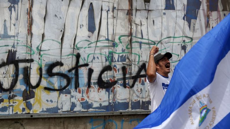 Un hombre participa en una vigilia para conmemorar los 100 días de protestas contra el régimen del líder nicaragüense Daniel Ortega junto a un grafiti que dice "Justicia", en Managua el 26 de julio de 2018. (Imagen MARVIN RECINOS/AFP a través de Getty Images)