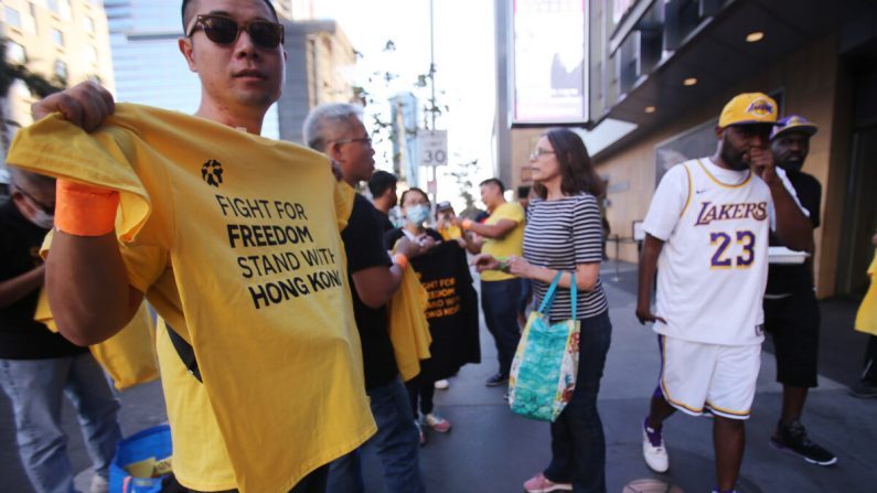 Un activista pro-Hong Kong (L) reparte camisetas antes del partido inaugural de la temporada de Los Angeles Lakers contra los LA Clippers fuera del Staples Center en Los Ángeles el 22 de octubre de 2019 (Mario Tama/Getty Images)