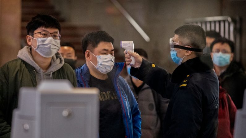 Un pasajero chino que acaba de llegar en el último tren bala de Wuhan a Beijing es revisado por un trabajador de la salud en una estación de tren de Beijing el 23 de enero de 2020 en Beijing, China. (Foto de Kevin Frayer/Getty Images)