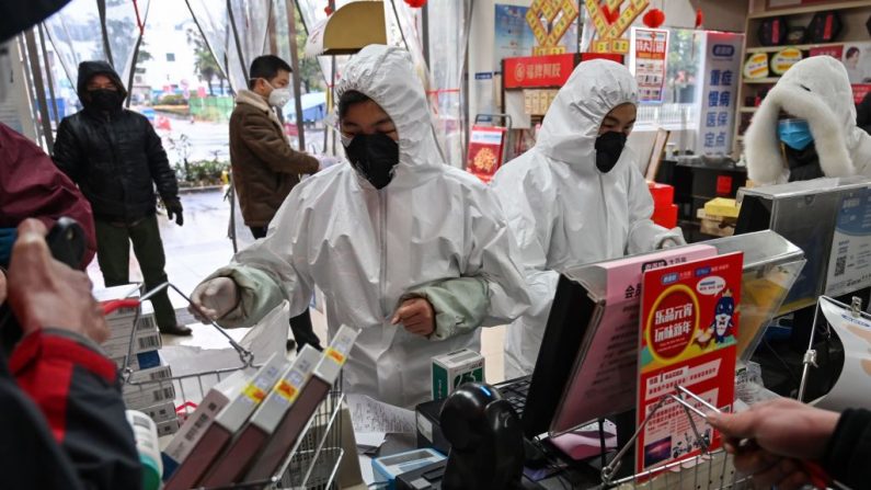 Trabajadores de la farmacia usan ropa de protección y máscaras para atender a los clientes en Wuhan el 25 de enero de 2020. (Hector Retamal/AFP vía Getty Images)