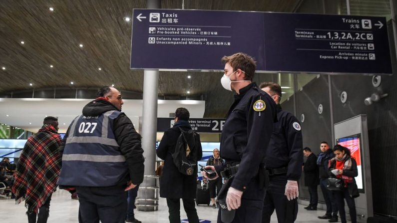 Policías con máscaras protectoras patrullan en la terminal de llegada del aeropuerto Charles De Gaulle, en Roissy-en-France, Francia, el 26 de enero de 2020. (Alain Jocard/AFP/Getty Images)