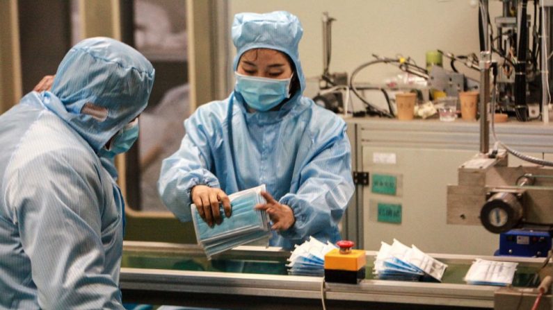 Esta foto tomada el 26 de enero de 2020 muestra a los trabajadores produciendo mascarillas, para apoyar el suministro de materiales médicos durante un brote de virus mortal que comenzó en Wuhan. (Foto ilustrativa de STR/AFP via Getty Images)