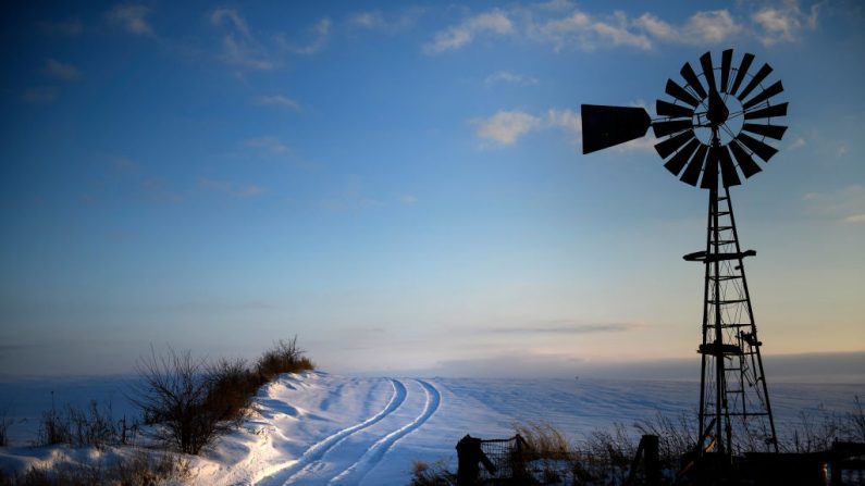 En esta foto de archivo se ve un molino de viento con huellas de neumáticos frescos en la nieve en un campo de cultivo el 25 de enero de 2020 en West Liberty, Iowa. (Foto de BRENDAN SMIALOWSKI/AFP a través de Getty Images)