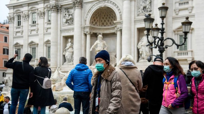 Los turistas con máscaras respiratorias recorren la Fontana de Trevi en el centro de Roma el 31 de enero de 2020. (FILIPPO MONTEFORTE/AFP vía Getty Images)