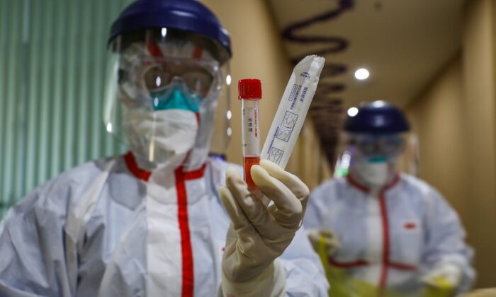 Miembro del personal médico mostrando un tubo de ensayo después de tomar muestras de una persona para ser analizadas en busca del nuevo coronavirus en una zona de cuarentena en Wuhan, China, el 4 de febrero de 2020. (STR/AFP vía Getty Images)