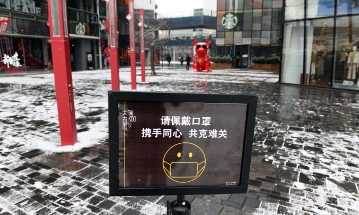 Un cartel insta a los visitantes a usar mascarillas faciales en la entrada de un centro comercial completamente vacío en Beijing, el 5 de febrero de 2020. (Greg Baker/AFP vía Getty Images)