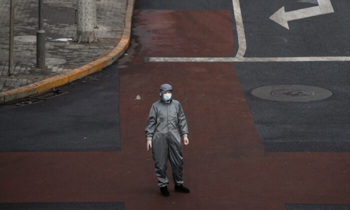 Una mujer china lleva un traje protector y una máscara mientras espera a cruzar la intersección de una calle casi vacía en Beijing, China, el 8 de febrero de 2020. (Kevin Frayer/Getty Images)