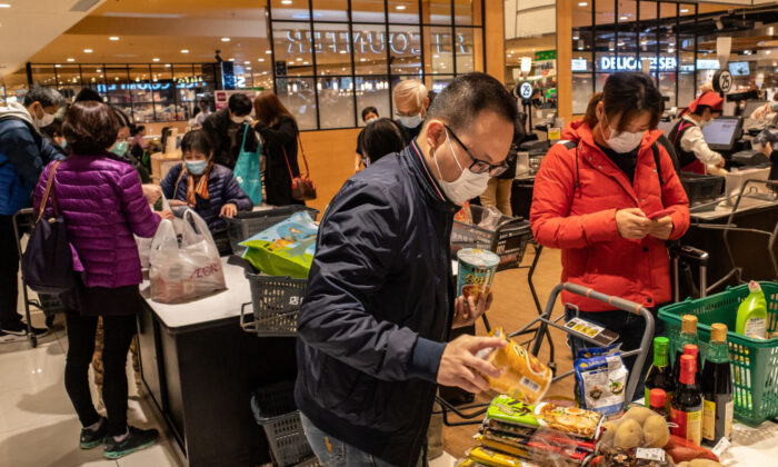 Varias personas con máscaras faciales embolsan sus compras en una tienda de comestibles en Hong Kong el 9 de febrero de 2020. (Anthony Kwan/Getty Images)