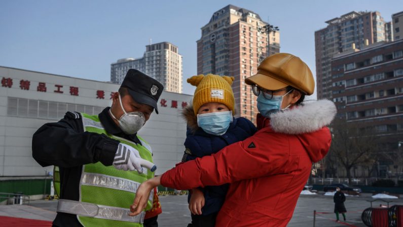 Una mujer china usa una máscara protectora mientras le controlan la temperatura antes de ingresar a un parque con su hijo en Beijing, China, el 9 de febrero de 2020. (Kevin Frayer / Getty Images)
