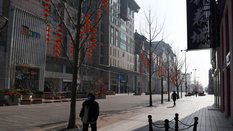 Una mujer lleva una mascarilla facial protectora mientras camina por la calle comercial Wangfujing ahora desierta y que antes era una calle bulliciosa en el centro de Beijing el 10 de febrero de 2020. (Foto de GREG BAKER/AFP vía Getty Images)