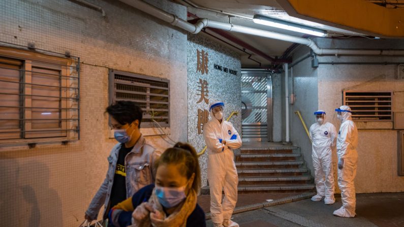 Los residentes que salen de Hong Mei House y funcionarios con equipo de protección hacen guardia frente a una entrada, en la urbanización Cheung Hong en el distrito de Tsing Yi, el 11 de febrero de 2020 en Hong Kong, China. (Foto de Billy H.C. Kwok/Getty Images)