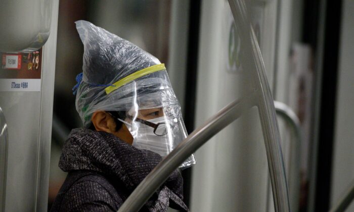 Un pasajero del metro lleva una mascarilla entre otros artículos de protección en Shanghai, China, el 12 de febrero de 2020. (NOEL CELIS/AFP vía Getty Images)