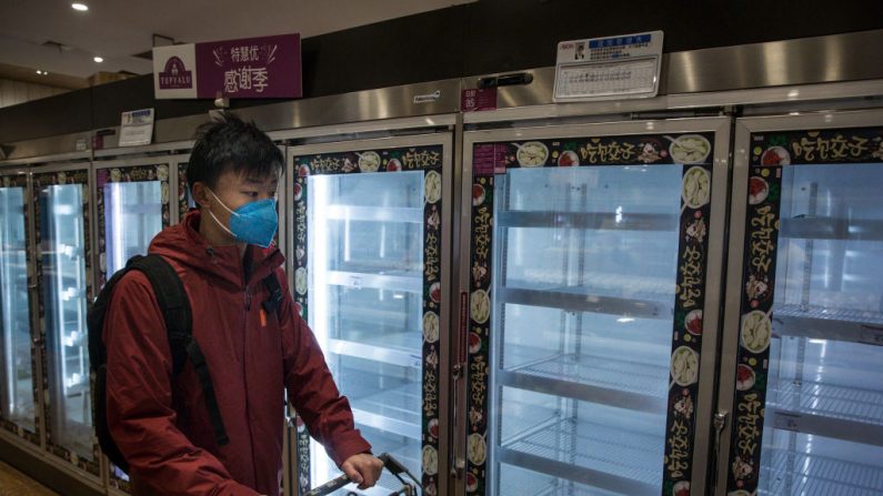 Un residente usa una máscara protectora al pasar por los estantes vacíos del supermercado el 12 de febrero de 2020 en Wuhan, provincia de Hubei, China. (Getty Images)