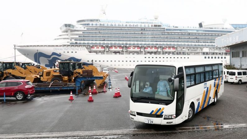 Un autobús con un conductor (Izq.) que lleva equipo de protección sale del muelle junto al crucero Diamond Princess, que tiene alrededor de 3600 personas en cuarentena a bordo debido a los temores del nuevo coronavirus COVID-19, en la Terminal de Cruceros del Muelle Daikoku en el puerto de Yokohama el 16 de febrero de 2020. (BEHROUZ MEHRI/AFP a través de Getty Images)
