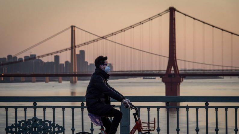 Un hombre con una máscara protectora va sobre una bicicleta en Wuhan, en la provincia central china de Hubei, el 17 de febrero de 2020. (STR / AFP a través de Getty Images)