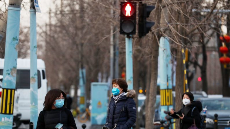 Mujeres chinas usan una máscara mientras esperan para cruzar una calle en Beijing el 18 de febrero de 2020. (Lintao Zhang/Getty Images)