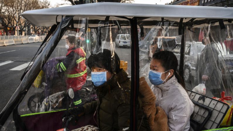 Una mujer y una niña chinas usan máscaras protectoras mientras viajan en un triciclo cubierto de plástico en Beijing, China, el 19 de febrero de 2020. (Kevin Frayer / Getty Images)
