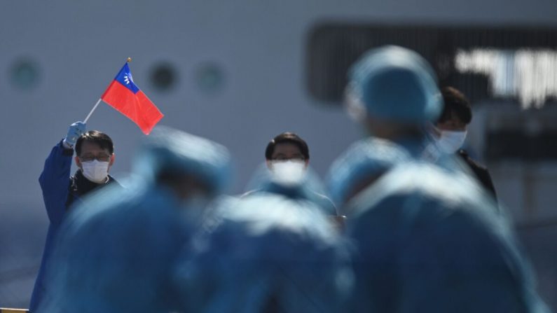 Un hombre sostiene una bandera de Taiwán cuando los pasajeros desembarcan del crucero Diamond Princess, en cuarentena por temor a un nuevo coronavirus COVID-19, en la terminal de cruceros del muelle Daikoku en Yokohama el 21 de febrero de 2020. (Philip Fong/AFP a través de Getty Images)