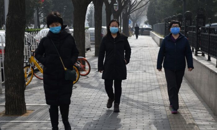 Transeuntes de una calle de Beijing llevan mascarillas el 21 de febrero de 2020 como protección contra la difusión del nuevo coronavirus chino, Covid-19. (Greg Baker/AFP vía Getty Images)