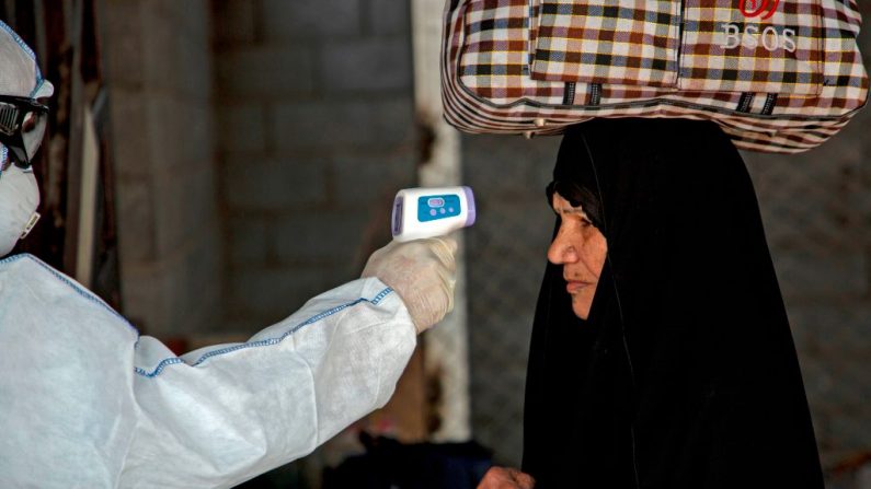 Un miembro del personal médico iraquí verifica la temperatura de una pasajera, en medio del nuevo brote de coronavirus, a su llegada al cruce fronterizo de Shalamcha entre Irak e Irán, el 20 de febrero de 2020. (Essam al-Sudani / Reuters)