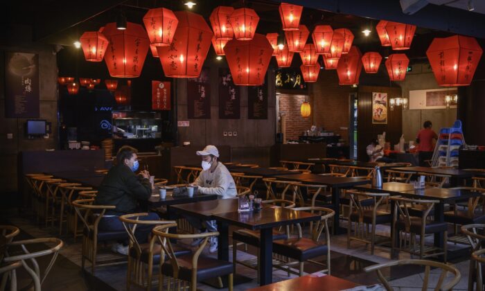 Dos hombres chinos se sientan en un restaurante casi vacío dentro de un centro comercial usualmente ocupado en Beijing el 22 de febrero de 2020. (Kevin Frayer/Getty Images)