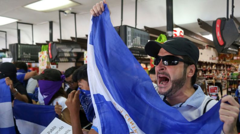 Manifestantes de la oposición gritan consignas a la policía antidisturbios que permanece fuera de un supermercado que bloquea su entrada en Managua, Nicaragua, el 22 de febrero de 2020. (INTI OCON/AFP/Getty Images)