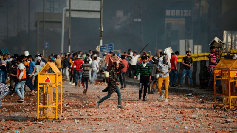 Los manifestantes se reúnen a lo largo de un camino sembrado de piedras tras los enfrentamientos entre partidarios y opositores de una nueva ley de ciudadanía, en la zona de Bhajanpura de Nueva Delhi el 24 de febrero de 2020, antes de la llegada del presidente de los Estados Unidos a la ciudad. (Foto de SAJJAD HUSSAIN/AFP vía Getty Images)