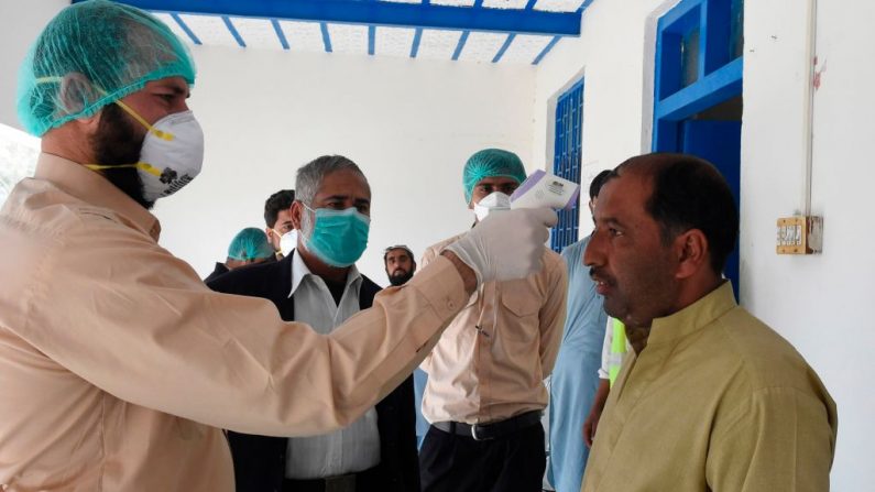 Un médico comprueba la temperatura corporal de un hombre que regresa de Irán en una zona de cuarentena para detectar el coronavirus COVID-19 en la ciudad de Taftan, en la frontera entre Pakistán e Irán, el 25 de febrero de 2020. (BANARAS KHAN/AFP vía Getty Images)