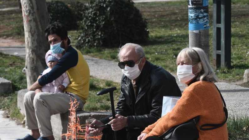 Personas con máscaras faciales se sientan fuera del hospital de Ahepa en Salónica el 26 de febrero de 2020, el mismo día en que el país informó su primer caso del nuevo coronavirus. (Sakis Mitrolidis / AFP a través de Getty Images)