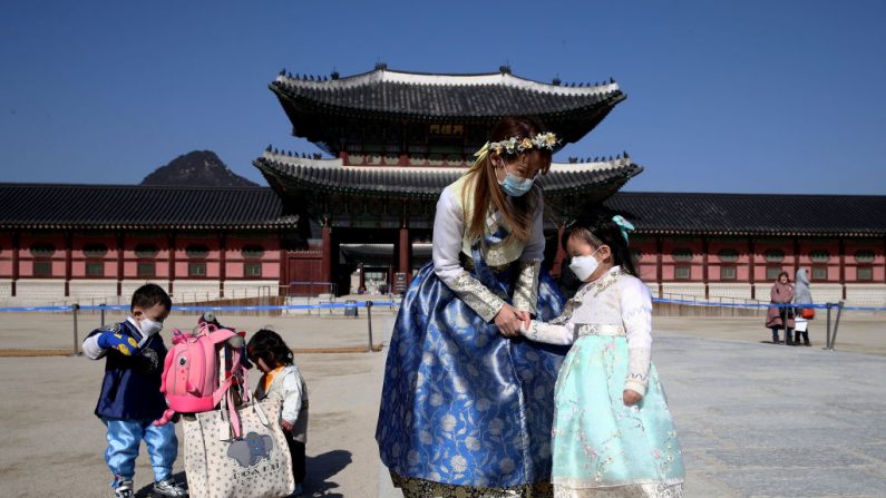 Las personas con vestidos tradicionales coreanos "Hanbok" usan máscaras faciales como precaución contra el nuevo coronavirus,frente al Palacio Real de Gyeongbokgung el 3 de febrero de 2020 en Seúl, Corea del Sur. (Chung Sung-Jun/Getty Images)
