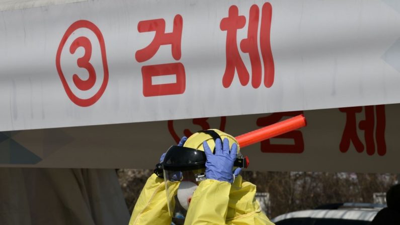Un miembro médico que usa equipo de protección guía a los conductores con síntomas sospechosos del coronavirus COVID-19, en una instalación de prueba en Goyang, al norte de Seúl, el 29 de febrero de 2020. (Jung Yeonje-JE/AFP vía Getty Images)