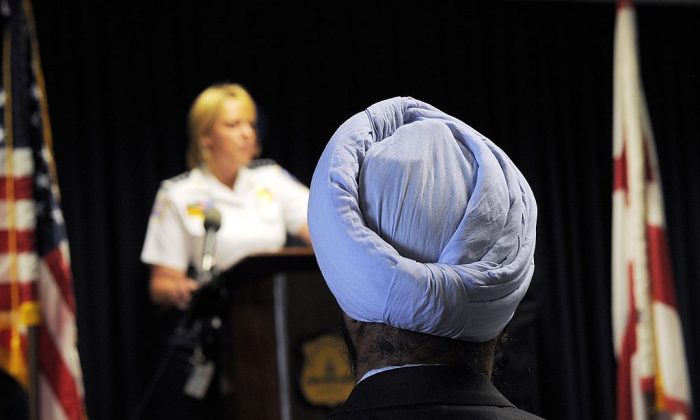 Un hombre sikh con turbante escucha mientras la Jefa de la Policía Metropolitana, Cathy Lanier, habla para dar a conocer las nuevas reglas de uniforme y apariencia del Departamento de Policía Metropolitana (MPD) en la sede del MPD en Washington, DC, el 16 de mayo de 2012. El MPD se convirtió en el primer gran departamento de policía en los EE.UU. en permitir proactivamente a los sikh estadounidenses servir como oficiales a tiempo completo mientras mantienen sus artículos de fe. FOTOGRAFÍA AFP /JEWEL SAMAD (Crédito foto: JEWEL SAMAD/AFP/GettyImages)