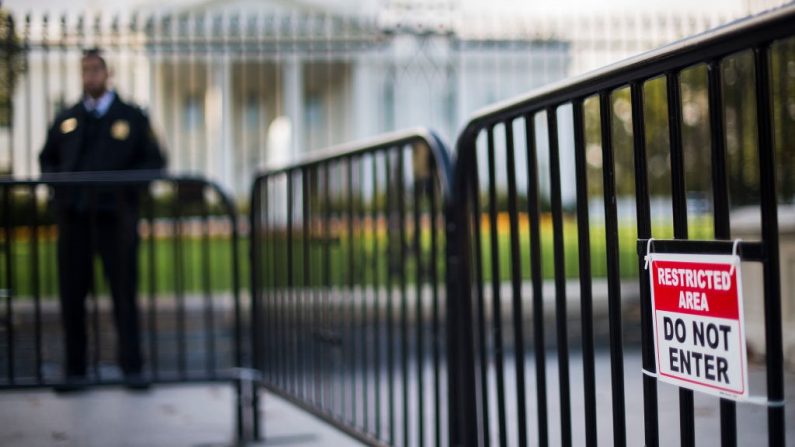 Un oficial del Servicio Secreto de la División Uniformada de EE.UU. se encuentra entre una barricada temporal y la línea de la valla de la Casa Blanca en Washington, DC, el 23 de octubre de 2014. Un sospechoso que escaló la valla de la Casa Blanca el 22 de octubre fue atrapado por agentes del Servicio Secreto y perros, dijo un portavoz de la agencia de élite. (Foto de JIM WATSON/AFP vía Getty Images)